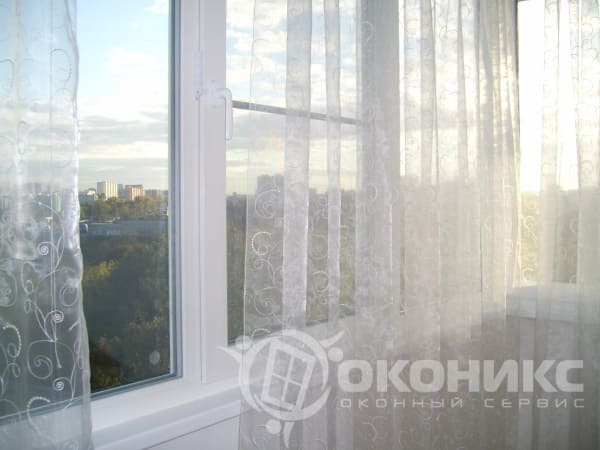 Пример установки пластикового окна с белой фурнитурой. Лёгкие шторы создают уютную атмосферу — работа компании «Оконикс».