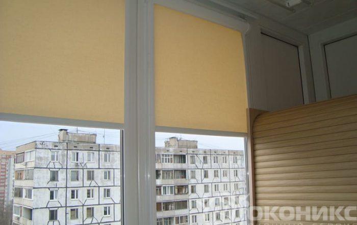 Остеклённый балкон с рулонными шторами пастельного оттенка — демонстрация практичности и стиля в оформлении оконных проёмов.